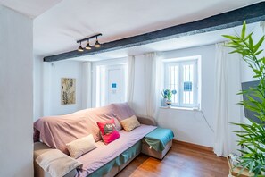 A cozy room with a sofa, a window with curtains, a plant, and a wall-mounted artwork. - Cubo's Coin Center Terrace House / urban / close to shops / free wifi (Coín)