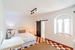 A hotel room with a bed, bedside table, lamp, and a checkered floor. - Cubo's Coin Center Terrace House / urban / close to shops / free wifi (Coín)