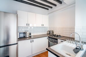 A modern kitchen with white cabinets, a stainless steel refrigerator, a built-in oven, a microwave, and a sink with a faucet. - Cubo's Coin Center Terrace House / urban / close to shops / free wifi (Coín)