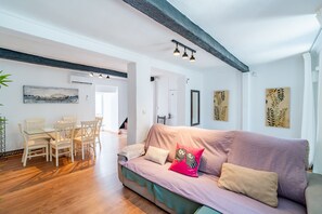 A modern living room with a wooden floor, a sofa, a dining table with chairs, and artwork on the walls. - Cubo's Coin Center Terrace House / urban / close to shops / free wifi (Coín)