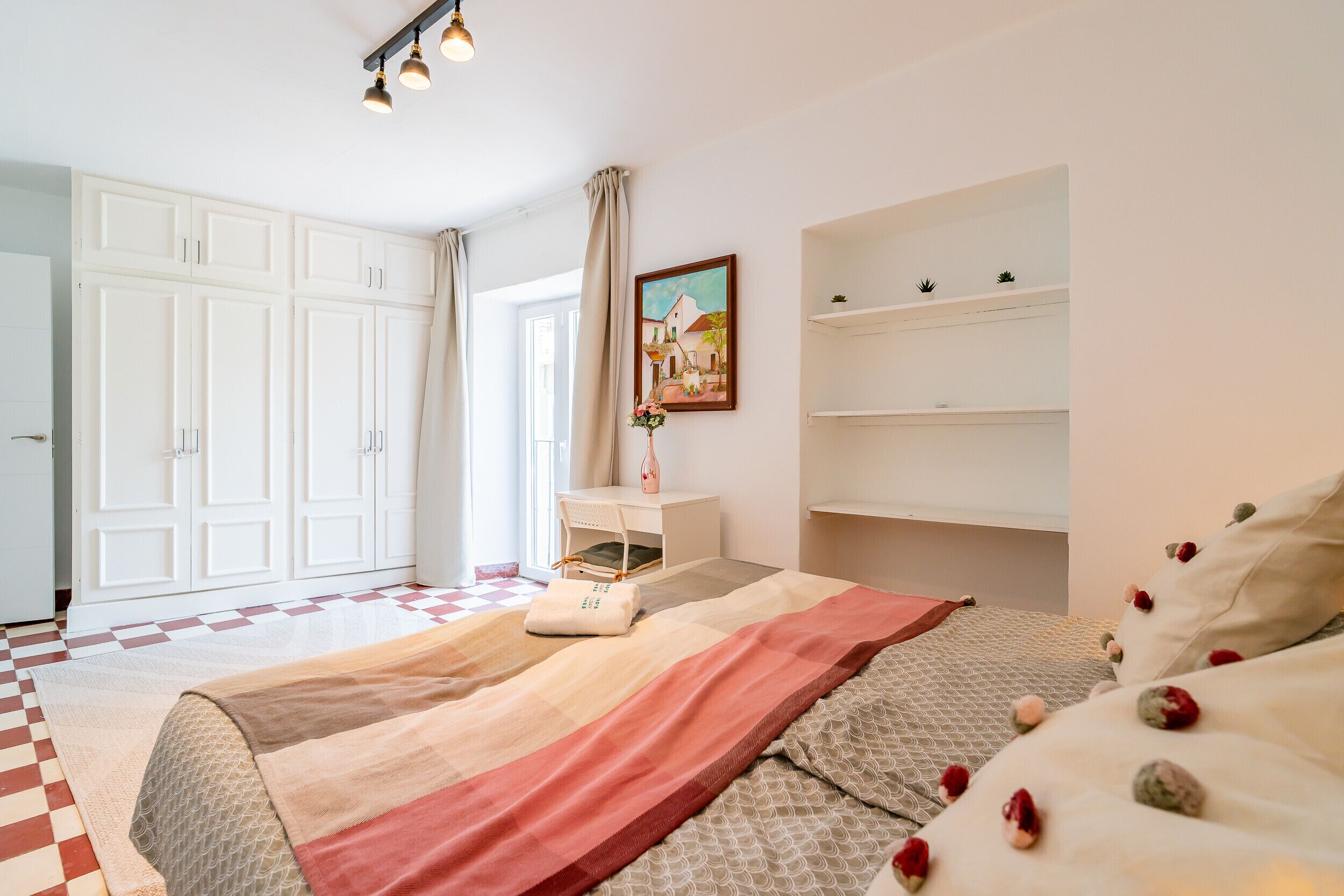 Une chambre à coucher avec un lit, un bureau, une chaise, une armoire et un tableau accroché au mur.