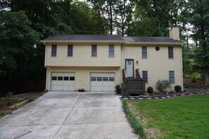 Ein zweistöckiges Haus mit Garage, Veranda und kleinem Garten.