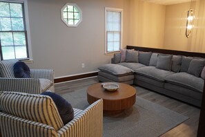 Ein Wohnzimmer mit einem Ecksofa, einem runden Couchtisch und zwei Sesseln.