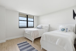 A bedroom with two single beds, a large window with a view, and a white ceiling. - Spectacular Gulf of America beach front condo with unforgettable views (Marco Island)