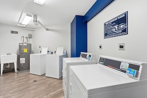 A laundry facility with multiple washing machines, a drying machine, a sink, and a blue wall with a safety sign. - Spectacular Gulf of America beach front condo with unforgettable views (Marco Island)