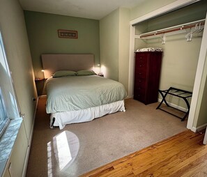 A bedroom with a bed, bedside lamps, a wardrobe, and a closet with hanging clothes. - Walk to The Barlow & Downtown  -  Bright 2BR/2BA Wine Country Retreat (Sebastopol)