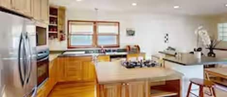 Een moderne keuken met houten kastjes, een roestvrijstalen koelkast en een centraal kookeiland met barkrukken.