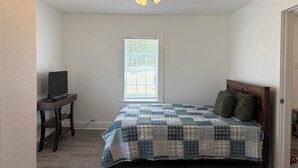 A bedroom with a bed, a desk, a ceiling fan, and a window. - Route 66 Retreat (Vega)