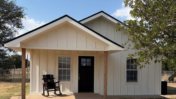 A single-story house with a front porch, a black door, and a small front yard. - Route 66 Retreat (Vega)