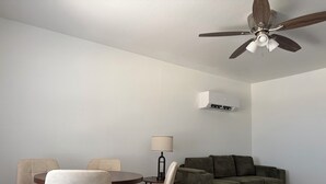 A modern living room with a ceiling fan, a sofa, a dining table with chairs, and an air conditioning unit. - Route 66 Retreat (Vega)