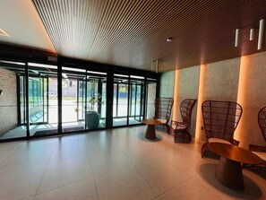 Interior moderno com entrada de vidro, área de estar e placa com a inscrição 'SAIDA'.