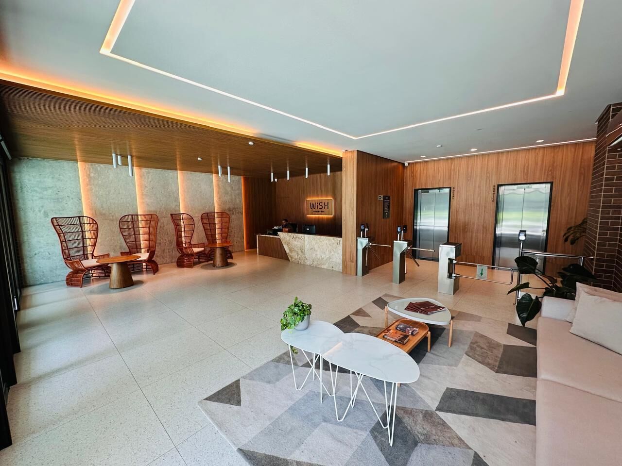 A modern hotel lobby with a reception desk, seating area, and elevators.