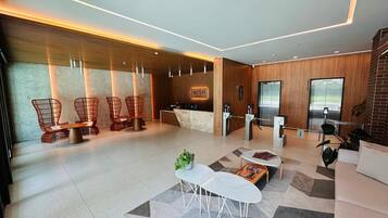 Um saguão de hotel moderno com balcão de recepção, área de estar e elevadores.