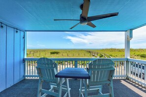 Un espace extérieur aménagé, abrité et doté de deux fauteuils Adirondack et d’une table, offrant une vue sur un paysage verdoyant.