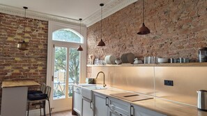 A kitchen with a brick wall, wooden countertop, and hanging pendant lights. - Luxury Sea View Historic Apartment (Ramsgate)