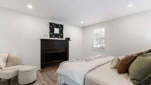 A bedroom with a bed, a chair, a fireplace, and a window. - Home Away From Home in Nashville 3B 2B W/ Large Fenced in Back Yard (Nashville)