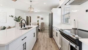 A modern kitchen with white cabinetry, a stainless steel refrigerator, and a built-in oven. - Home Away From Home in Nashville 3B 2B W/ Large Fenced in Back Yard (Nashville)