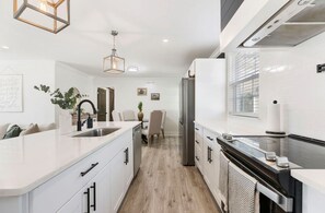 Eine moderne Küche mit weißen Schränken, einem Edelstahlkühlschrank und einem eingebauten Backofen.