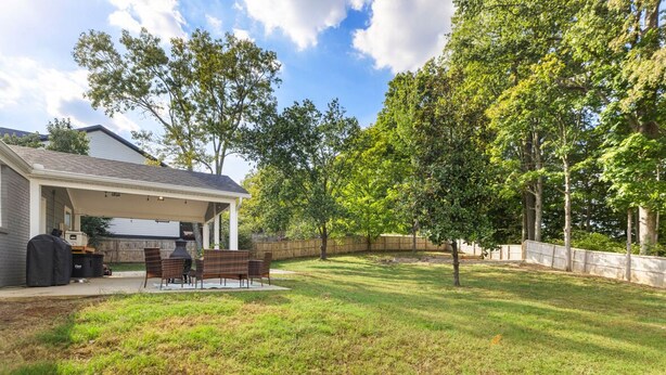 A backyard with a covered patio, a barbecue grill, and a seating area. - Home Away From Home in Nashville 3B 2B W/ Large Fenced in Back Yard (Nashville)