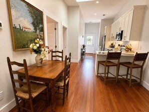 A dining area with a wooden table and chairs, a vase of flowers, and a painting on the wall. - Stunning Home Near Starland | 2 King Beds (Savannah)