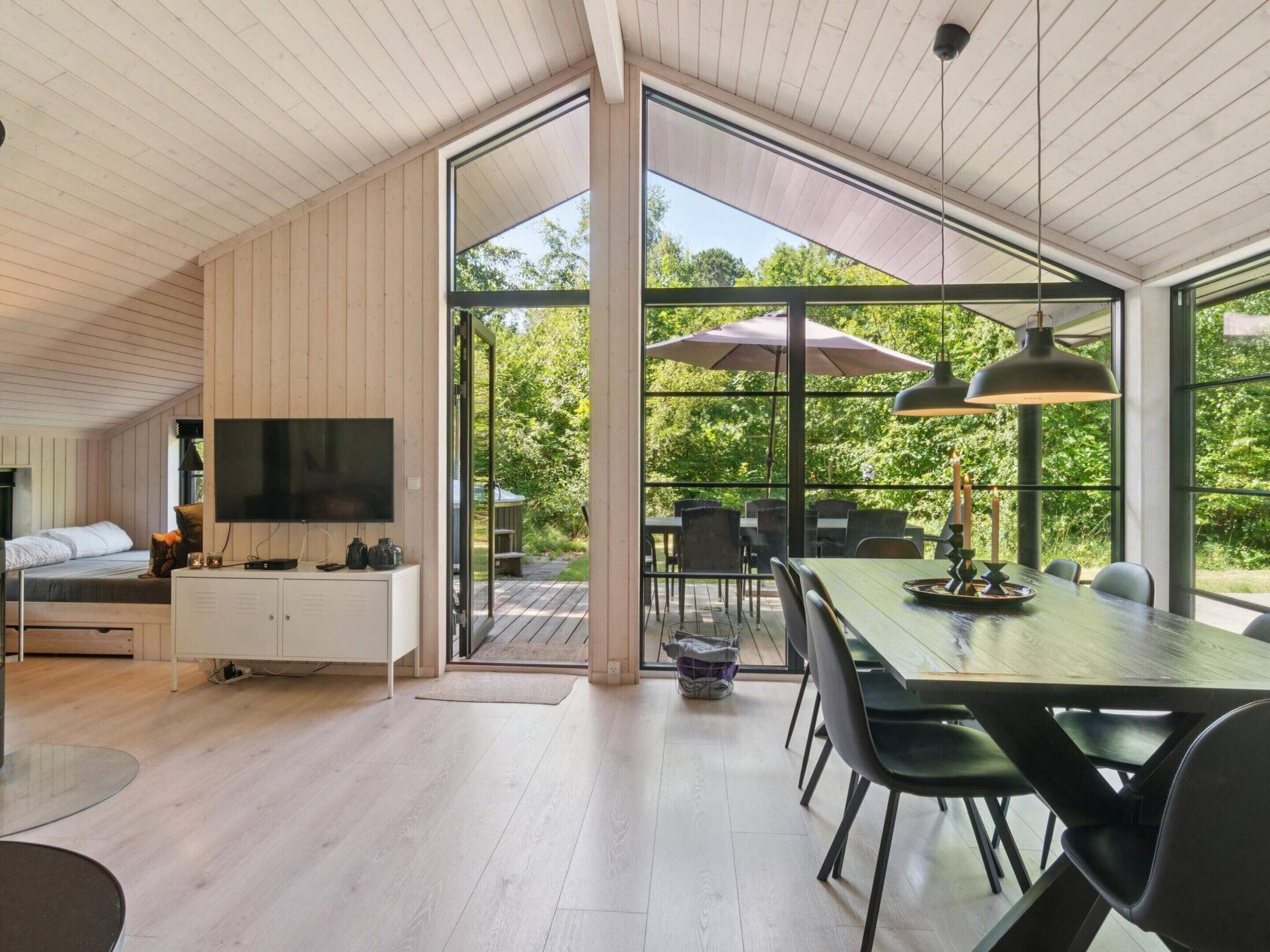 Un intérieur moderne comprenant un coin repas, un téléviseur et une vue sur l’extérieur.