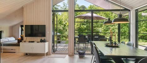 A modern interior with a dining area, a television, and a view of the outdoors.
