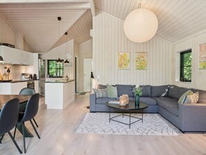 A modern interior with a dining area, kitchen, and living room with a sofa and coffee table. - 4 Star Holiday Home in Vig (Vig)