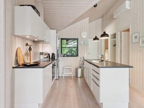 A modern kitchen with white cabinetry, a stainless steel sink, and a window with a view of greenery. - 4 Star Holiday Home in Vig (Vig)