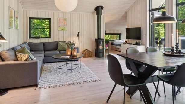 A modern living room with a sofa, coffee table, and dining area. - 4 Star Holiday Home in Vig (Vig)