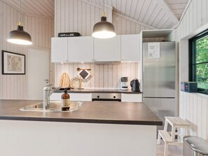 A modern kitchen with a central island, stainless steel appliances, and wooden accents. - 4 Star Holiday Home in Vig (Vig)