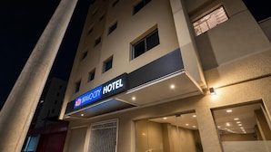 L’entrée d’un hôtel, avec une enseigne indiquant « BRAVOARY HOTEL » et une porte vitrée donnant accès à l’intérieur.
