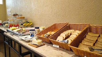 A buffet with various food items and bread baskets.