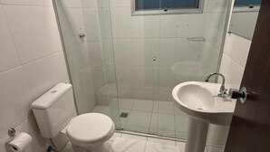 Une salle de bain avec une douche à parois de verre, des toilettes et un lavabo.