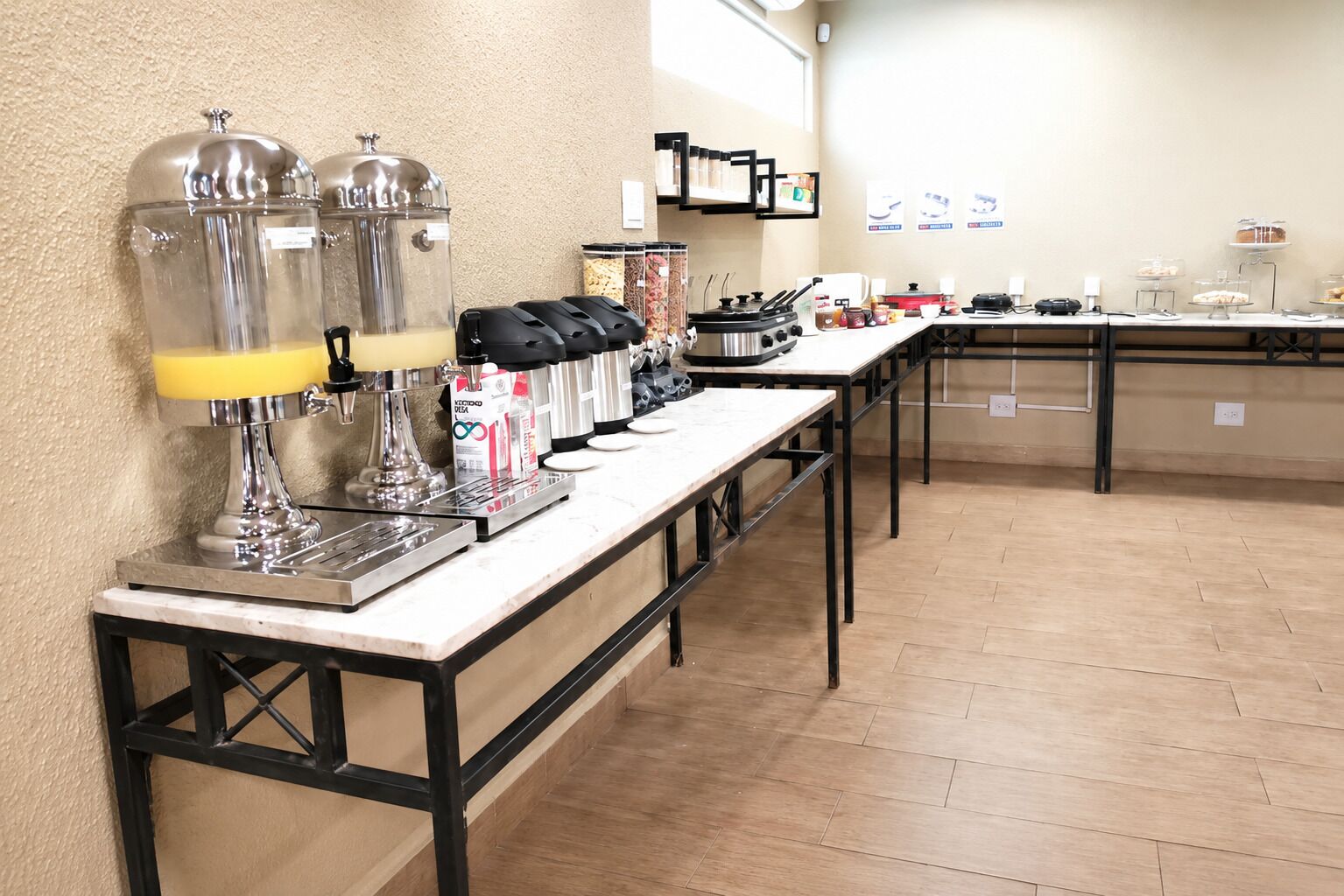 Montaje de bufé con estaciones de autoservicio, incluyendo máquinas de café y una variedad de alimentos.