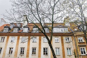 Ein mehrstöckiges Gebäude mit einer Reihe von Fenstern und einem Baum im Vordergrund.