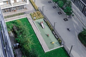 An aerial view of a modern building with a rooftop garden, a children's play area, and a paved walkway. - House in Landunvez near Plage de Penfoul (Warszawa)