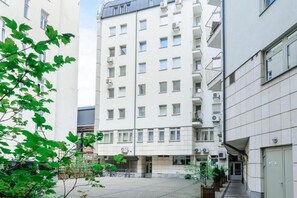 Ein mehrstöckiges Wohngebäude mit Balkonen, einem verschlossenen Eingangsbereich und einem Innenhof.