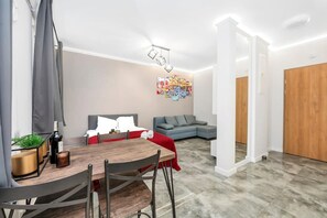 A modern living room with a dining area, grey sofa, and a red throw on the couch. - Stay with Free Parking (Łódź)