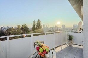 Ein Balkon mit Obstschale, Topfpflanze und Blick auf die Stadt.