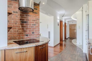 Eine moderne Küche mit Backsteinwand, Edelstahl-Dunstabzugshaube und einer gewölbten Arbeitsplatte.
