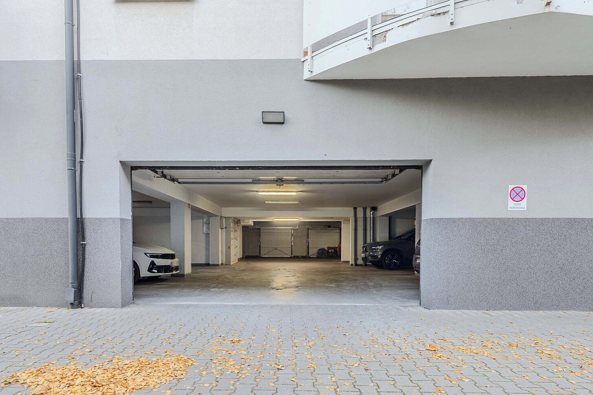 En infart till ett parkeringsgarage med en vit bil och en svart bil parkerade inuti.