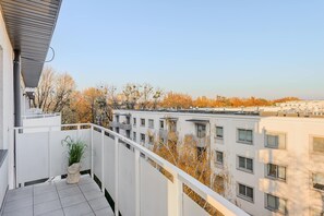 Ein Balkon mit Blick auf einen Gebäudekomplex und Herbstbäume.