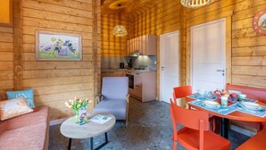A cozy cabin interior with a dining area, kitchen, and a living space with a sofa and a small table.