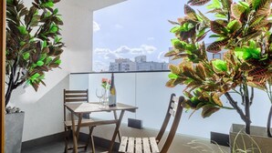 Un balcon avec une table et des chaises, des plantes en pot et une vue sur les immeubles.