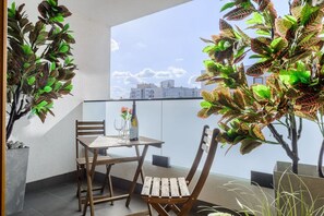 Ein Balkon mit Tisch und Stühlen, Topfpflanzen und Blick auf Gebäude.