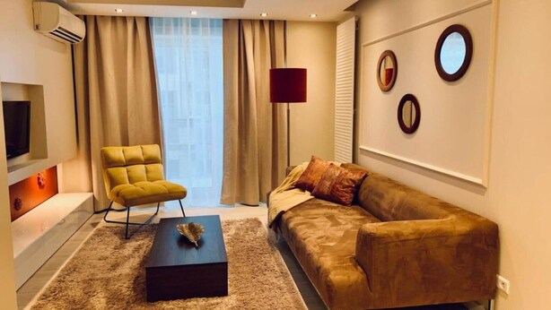 A modern living room with a sofa, armchair, coffee table, and a TV. - Central Warsaw Home with Pool (Warszawa)