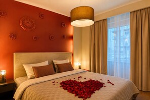 A hotel room with a bed, decorative wall panels, a large window with curtains, and a hanging light fixture. - Central Warsaw Home with Pool (Warszawa)