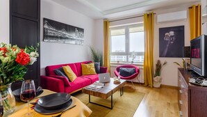 A modern living room with a red sofa, a coffee table, a laptop, and a television. - Warsaw Home with City Views (Warszawa)