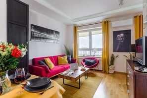 Ein modernes Wohnzimmer mit einem roten Sofa, einem Couchtisch, einem Laptop und einem Fernseher.