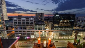 A rooftop terrace with a table set for two, candles, and a view of the cityscape at dusk. - Warsaw Home with City Views (Warszawa)